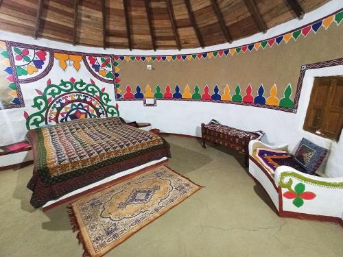 a bedroom with a bed with a decorated wall at Banni Village Resort - Rann Of Kutch in Bherandiāla