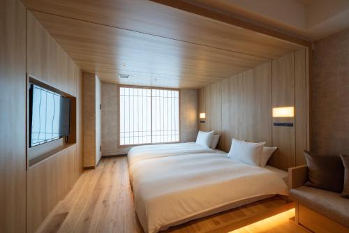 a bedroom with a large bed and a tv at Umekoji Potel KYOTO in Kyoto