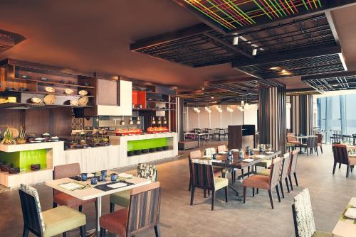a restaurant with tables and chairs and a kitchen at Novotel Hanoi Thai Ha in Hanoi