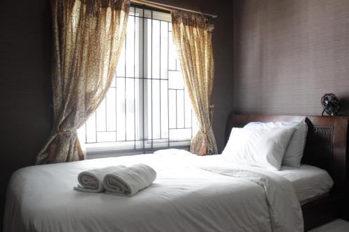 a bed with two towels on it with a window at Chic and Cozy 2BR Apartment at Pinewood Jatinangor near JATOS By Travelio in Cilimus 2