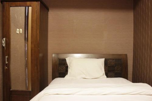 a bed with a silver headboard and a white pillow at Chic and Cozy 2BR Apartment at Pinewood Jatinangor near JATOS By Travelio in Cilimus 2