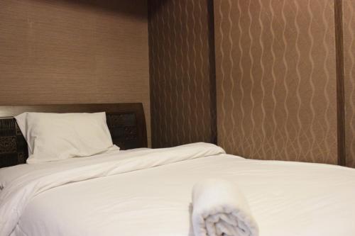 a hotel room with a bed with white sheets at Chic and Cozy 2BR Apartment at Pinewood Jatinangor near JATOS By Travelio in Cilimus 2