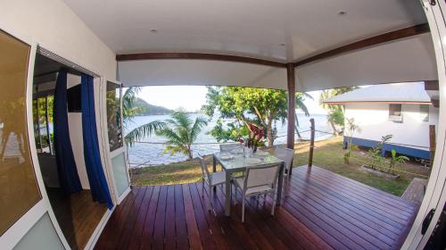 balkon ze stołem i krzesłami w domu w obiekcie Le Neliza Beach Lodge Raiatea w mieście Opoa