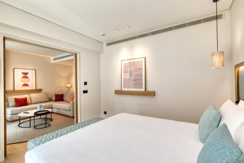 a bedroom with a white bed and a couch at Vathi Cove Luxury Resort & Spa in Chrysi Ammoudia