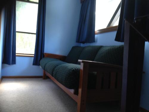 a living room with a couch and two windows at Canobolas Mountain Cabins in Lidster