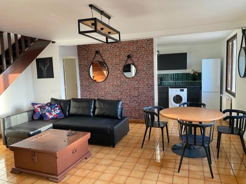 a living room with a black leather couch and a table at 014 CHIC & COSY GRAND APPART DUPLEX 76m2 WIFI SMART TV NETFLIX ET VUE PANORAMIQUE in Saint-Étienne
