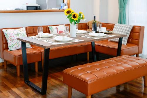 a dining room table with orange leather chairs and a table with at Sunset Beach Vacation House in Chatan