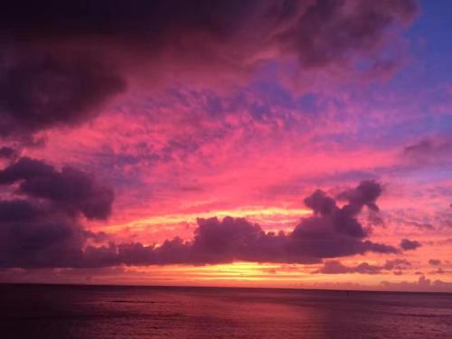 a sunset over the ocean with a pink at Sunset Beach Vacation House in Chatan