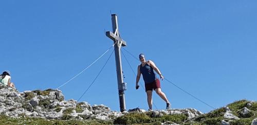 a man standing next to a cross on a hill at Landhaus Lenzenhof in Reit im Winkl