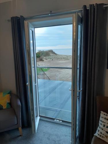 an open sliding glass door with a view of the beach at Seals Bacton in Bacton