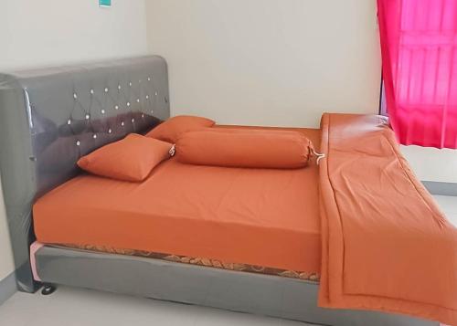 a bed with orange sheets and pillows in a room at Homestay Verisha Mitra RedDoorz in Singkawang