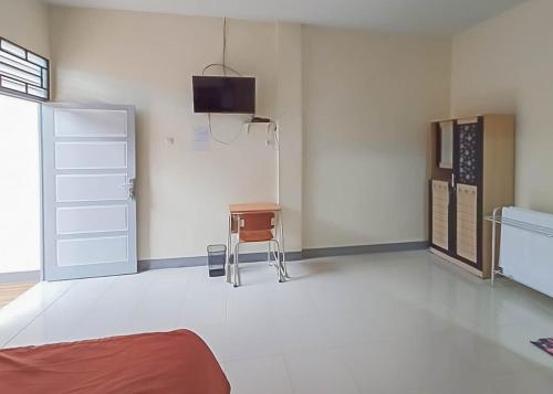 Habitación con mesa, silla y TV. en Homestay Verisha Mitra RedDoorz, en Singkawang