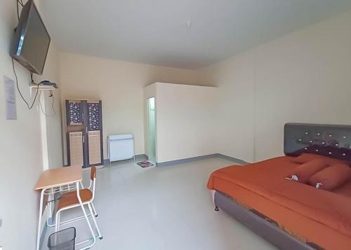 Habitación con cama, escritorio y TV. en Homestay Verisha Mitra RedDoorz, en Singkawang