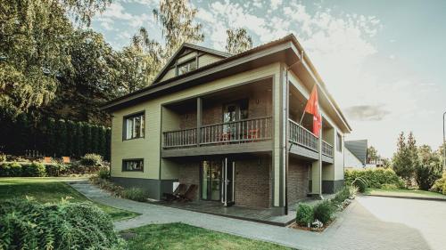 ein Haus mit einem Balkon und einer Flagge in der Unterkunft "Parko vila" Anykščiai - Odorata Gamtos SPA in Anykščiai