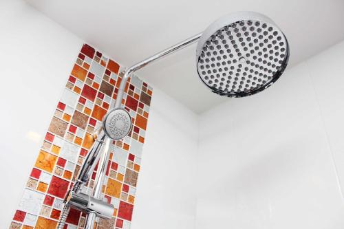 a shower head in a bathroom with a mosaic wall at Lub Sbuy House Hotel - SHA in Phuket Town