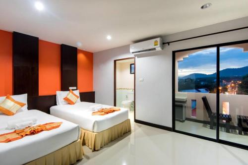 Dos camas en una habitación con una gran ventana. en Saiyuan Residence, en Kata Beach