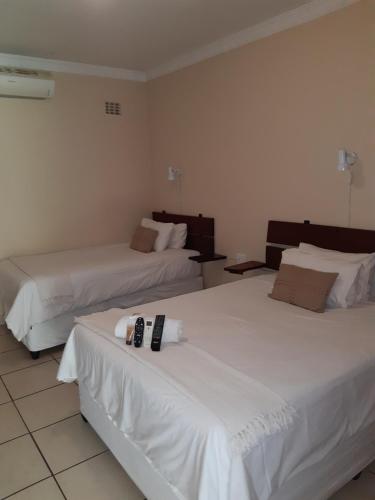 two beds in a hotel room with white sheets at Lepha Guest House in Onverwacht