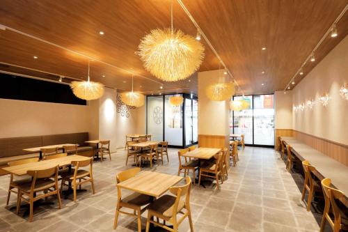 a restaurant with wooden tables and chairs and chandeliers at karaksa hotel Sapporo in Sapporo