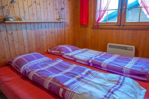two beds in a room with wooden walls at Chalet Allegra in Rosswald