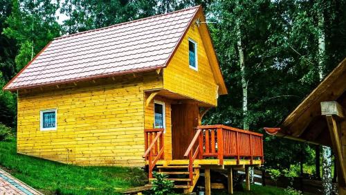 a small yellow house with a wooden deck at Grzywaczówka in Przesieka