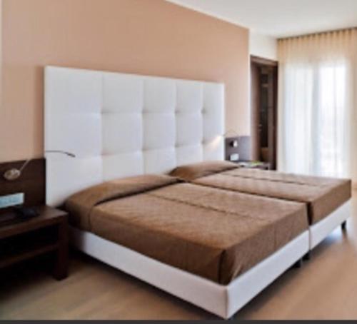 a large bed with a large headboard in a bedroom at Hotel Italy in Bibione