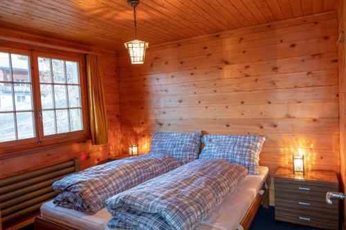 een slaapkamer met 2 bedden in een houten muur bij Chalet Elisabeth in Rosswald