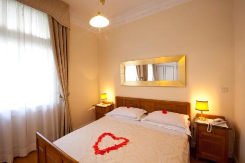 a bedroom with a bed with a red heart on it at Hotel Villa Westend in Merano