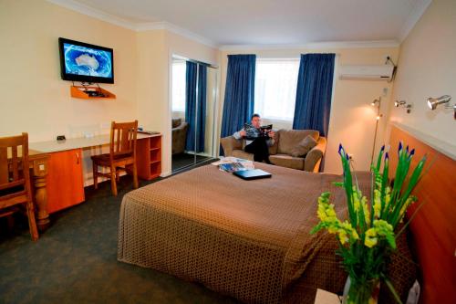 a hotel room with a woman sitting in a chair in a room at Scone Motor Inn & Apartments in Scone