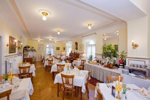 メラーノにあるHotel Villa Westendの白いテーブルクロスのテーブルと椅子が備わるレストラン