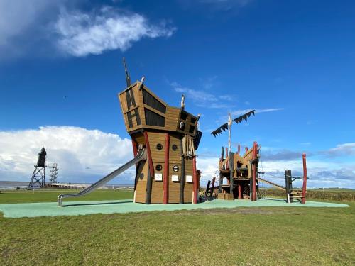 a playground with a house and a slide at Ferienwohnung am Deichweg in Cappel-Neufeld