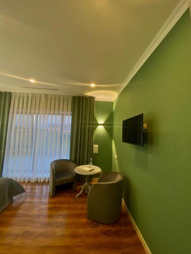 Habitación con paredes verdes, mesa y TV. en Royal Rest, 