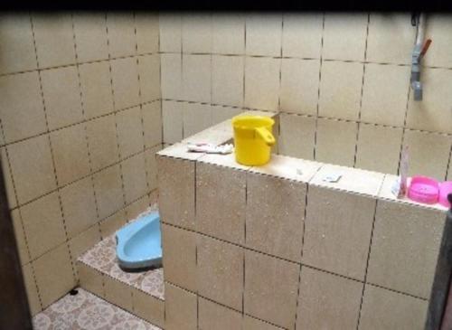 a bathroom with a toilet and a yellow bucket at Aren Homestay in Giripurno