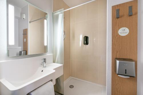 a bathroom with a sink and a shower with a mirror at B&B HOTEL Arcachon Gujan-Mestras in Gujan-Mestras