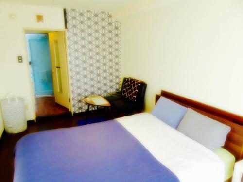 a bedroom with a bed and a chair in it at SONIC APARTMENT HOTEL in Dazaifu