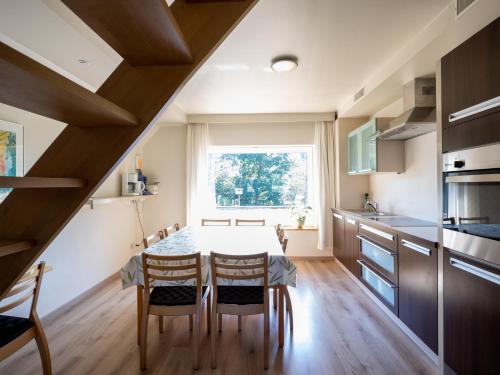 cocina con mesa, sillas y ventana en Holiday Home Op 't Busselen, en Opoeteren