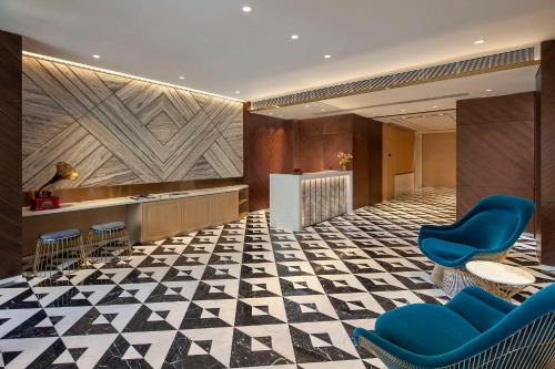 a lobby with blue chairs and a checkerboard floor at Hotel 1936 in Hong Kong