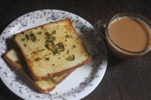 a sandwich on a plate next to a cup of coffee at Awesome Dormitory Male Only in Mumbai