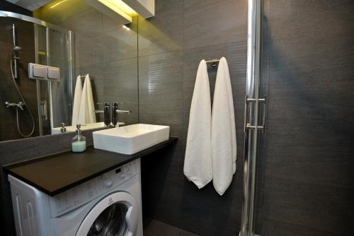 a bathroom with a washing machine and a sink at Apartamenty TOP Garbary in Poznań