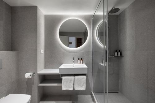 ein Bad mit einem Waschbecken und einer Dusche mit einem Spiegel in der Unterkunft Botanique Hotel Prague in Prag