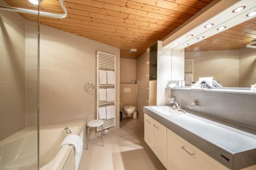 a bathroom with a tub and a sink and a mirror at Hotel Kreuz & Post Grindelwald in Grindelwald