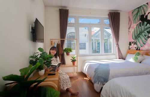 a young girl is sitting in a room with two beds at Moc Thach Hostel Dalat in Da Lat