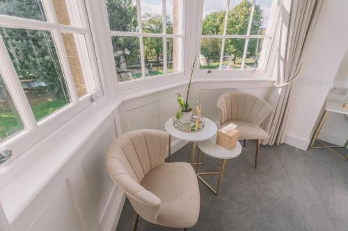 a room with two chairs and a table and two windows at Old Bank Rooms in Bourton on the Water