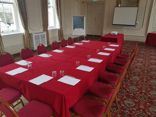 a long table in a room with red tables and chairs at George Hotel by Greene King Inns in Huntingdon