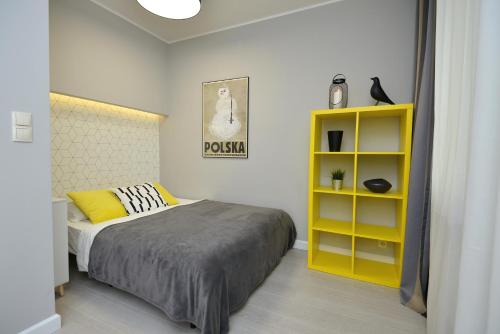 a bedroom with a bed and a yellow shelf at Apartamenty TOP Garbary in Poznań