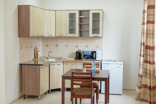 a small kitchen with a table and a sink at Sarai-Batu Guest House in Atyrau