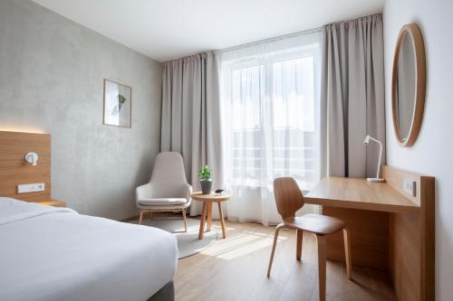 a hotel room with a bed and a desk and a window at Botanique Hotel Prague in Prague
