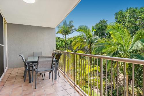 d'un balcon avec une table, des chaises et des palmiers. dans l'établissement Beachcomber on the Spit, à Mooloolaba