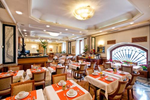 ein Restaurant mit Tischen, Stühlen und einem Kronleuchter in der Unterkunft Hotel Giolli Nazionale in Rom