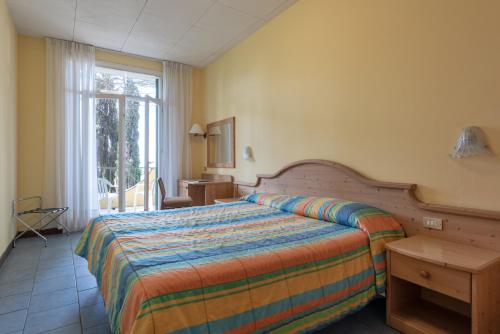 una camera da letto con un letto, un tavolo e una finestra di Hotel Marco Polo a Garda