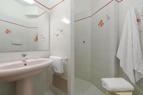 Baño blanco con lavabo y espejo en Hotel Marco Polo, en Garda